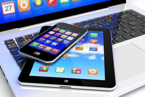 Tablet PC and mobile smartphone with colorful apps on a screen lying on laptop keyboard. Technology 3d concept